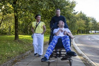 Joyful Spanish Cameroonian siblings enjoy a walk. One sibling, who has cerebral palsy, is in a