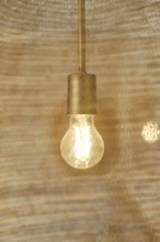 A warm, glowing light bulb hangs within a rustic hotel room, casting a cozy ambiance. The elegant