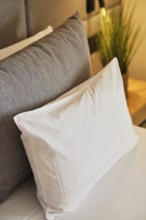 Modern hotel room featuring plush pillows, one with a textured gray cover on a neatly made bed. A