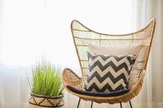 A beautifully decorated hotel room featuring a wicker chair, chevron-patterned cushion, and a woven