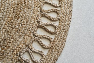 Detailed close-up of a braided jute rug showcasing its intricate woven design. The natural fibers