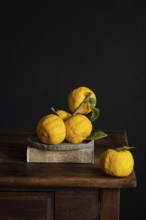 A rustic still life featuring vibrant yellow lemons with green leaves elegantly arranged atop a