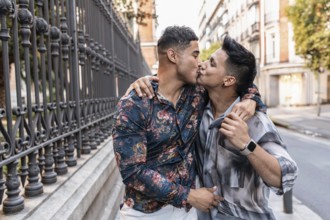 A romantic moment in Madrid as a couple shares a heartfelt kiss on a city street. Their stylish