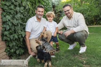 A joyful image of a gay couple with their son and two small dogs outdoors. They are surrounded by
