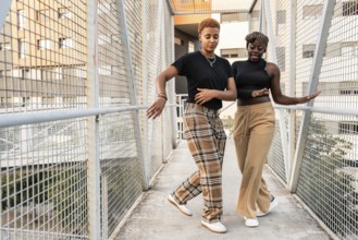 A joyful LGBT multiethnic couple dances on a city bridge, sharing a moment of connection and