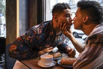 A loving latin gay couple shares a tender moment at a cafe, enjoying breakfast together. The