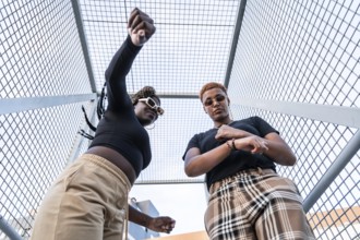 A lively LGBT multiethnic couple enjoys their day against an urban backdrop. They wear stylish