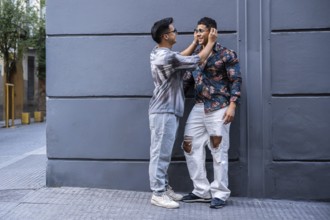 A latin gay couple enjoys a playful moment on an urban street, showing affection. They wear casual