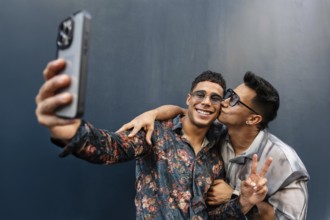 A joyful latin gay couple takes a selfie, capturing a moment of affection and happiness. One person