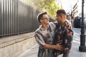 A joyful latin gay couple shares a warm embrace and smiles while walking on a sunny day in the
