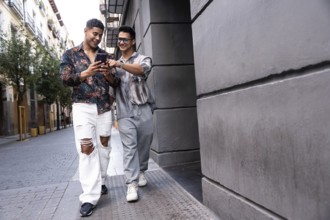 A joyful latin gay couple exploring Madrid, sharing moments and looking at a smartphone while