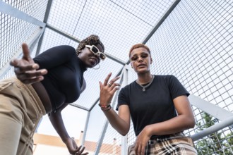 A dynamic LGBT multiethnic couple poses confidently in an urban setting. Both showcase unique