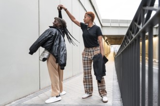 A happy LGBT multiethnic couple dances in an urban passageway, enjoying a playful moment together.