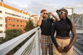 A fashionable LGBT multiethnic couple poses confidently on an urban rooftop, showcasing their