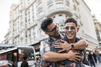 A joyful latin gay couple shares a playful embrace on a lively street in Madrid. The energy of the