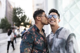 A happy latin gay couple enjoying an affectionate moment on a bustling street in Madrid, capturing