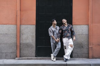 A joyful latin gay couple shares a tender moment holding hands, standing in front of a colorful