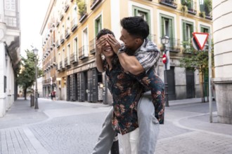 A happy latin gay couple enjoys a playful moment in the vibrant streets of Madrid. They are