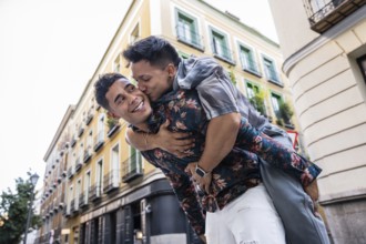 A joyful latin gay couple enjoys a playful moment on the streets of Madrid. They show affection