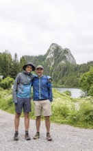 A father and son enjoy a hiking adventure at Lac de Taney, Switzerland, surrounded by lush greenery