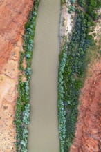 A striking aerial shot of the Rio San Juan winding through vibrant red rock landscapes, contrasted