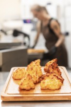 Freshly baked Italian pastries sit on a wooden board in a warm bakery A baker is seen working in