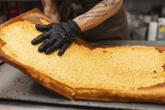 An artisan baker carefully handles a large sheet of golden-brown pastry in an Italian bakery The