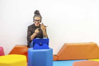 A woman with headphones and an tablet teaches sign language online, demonstrating gestures
