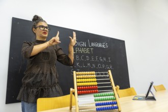 An instructor demonstrates sign language, using hand gestures to teach the alphabet The classroom