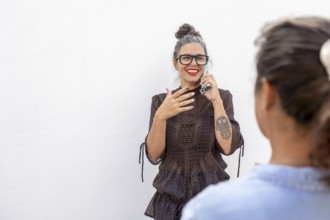 A smiling woman using sign language during a lesson She engages with another person, demonstrating