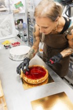 An artisan baker decorates a glossy fruit tart with fresh berries in an Italian bakery kitchen The