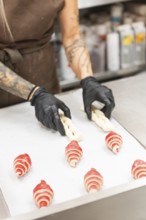 A skilled artisan wearing gloves crafts intricate pastries on a preparation table in an Italian
