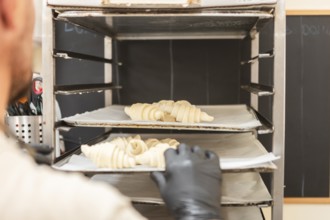 A baker places raw croissants onto a baking rack in an Italian bakery The scene captures the