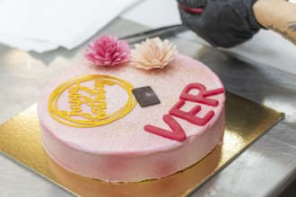 A beautifully crafted Italian birthday cake featuring pink floral decorations and a happy birthday