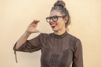 A woman with glasses and red lipstick enthusiastically demonstrates a sign language gesture