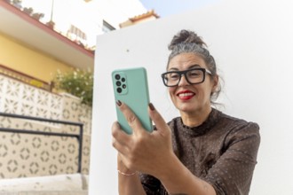 A woman is sitting outside, actively participating in an online sign language class using her