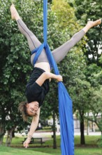 Aerialist performs acrobatics on blue fabric in a lively Bogota park The scene captures the blend
