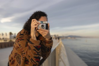 Casual moment of a young man enjoying photography by the scenic waterfront He is dressed in a cozy