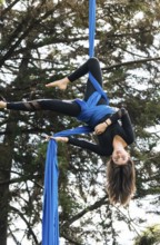 A skilled aerial performer demonstrates acrobatics on vibrant blue fabric in a tranquil Bogota
