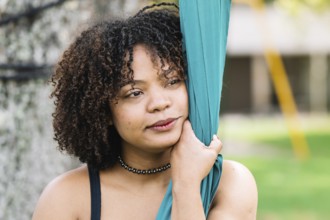 A black woman embraces silk fabric in a serene moment during a park acrobatics session in Bogota