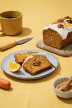A tasty carrot cake loaf topped with creamy frosting and walnuts, presented on a yellow linen