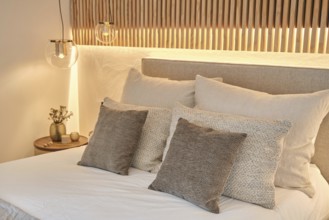 Modern bedroom featuring textured pillows, soft bedding, and ambient lighting with a wooden