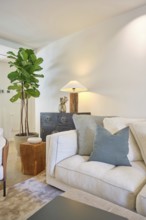 This cozy living room features a stylish beige sofa, a robust green fiddle leaf fig plant, and a