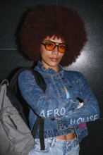 African descent woman with a voluminous afro hairstyle wearing orange sunglasses and a denim