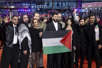 Actors and crew of the film Chronicles From the Siege hold a flag of Palestine on the Red Carpet