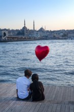 Istanbul, Turkey. 20th October 2019 A romantic couple sit beside the Golden Horn with a red heart