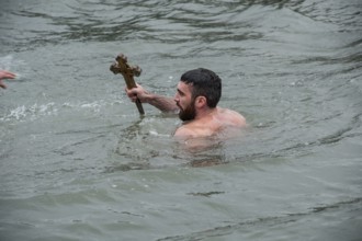 Istanbul, Turkey, January 6th 2017 A man holds a wooden cross after retrieving it from the Golden