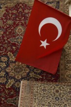 Istanbul, Turkey, February 23rd 2018. A Turkish flag and antique carpet for sale in a shop in the