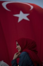 Istanbul, Turkey, July 17th 2016 Turkish Muslim Woman with red headscarf with Turkish flag behind