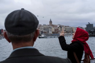 Istanbul, Turkey, February 23rd 2018. A Turkish Muslim woman taking photographs on the Golden Horn